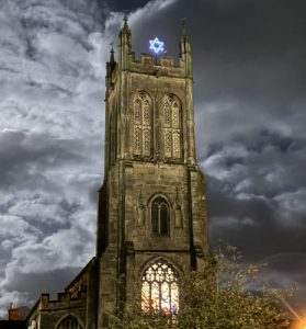 St Ben's tower by night, with our Advent and Christmas star shining on the top, the sky behind lit by the almost full moon.